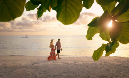 Couple enjoying a romantic beach walk at sunset after a Kenya Honeymoon Safari