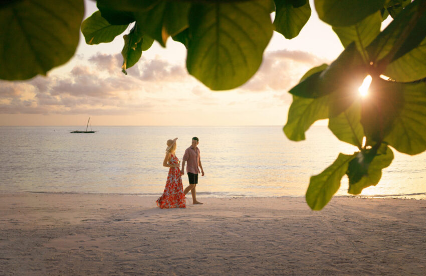 Couple enjoying a romantic beach walk at sunset after a Kenya Honeymoon Safari