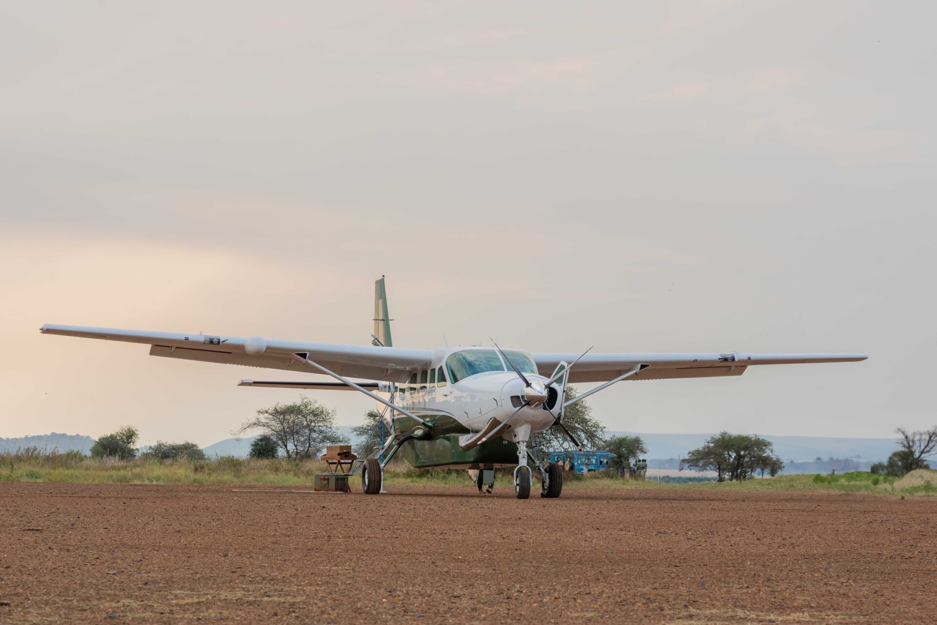 Small bush plane parked on a dirt airstrip surrounded by savanna